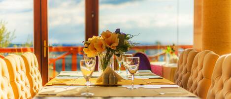 A dining table with a vase of flowers, two wine glasses, and a menu.