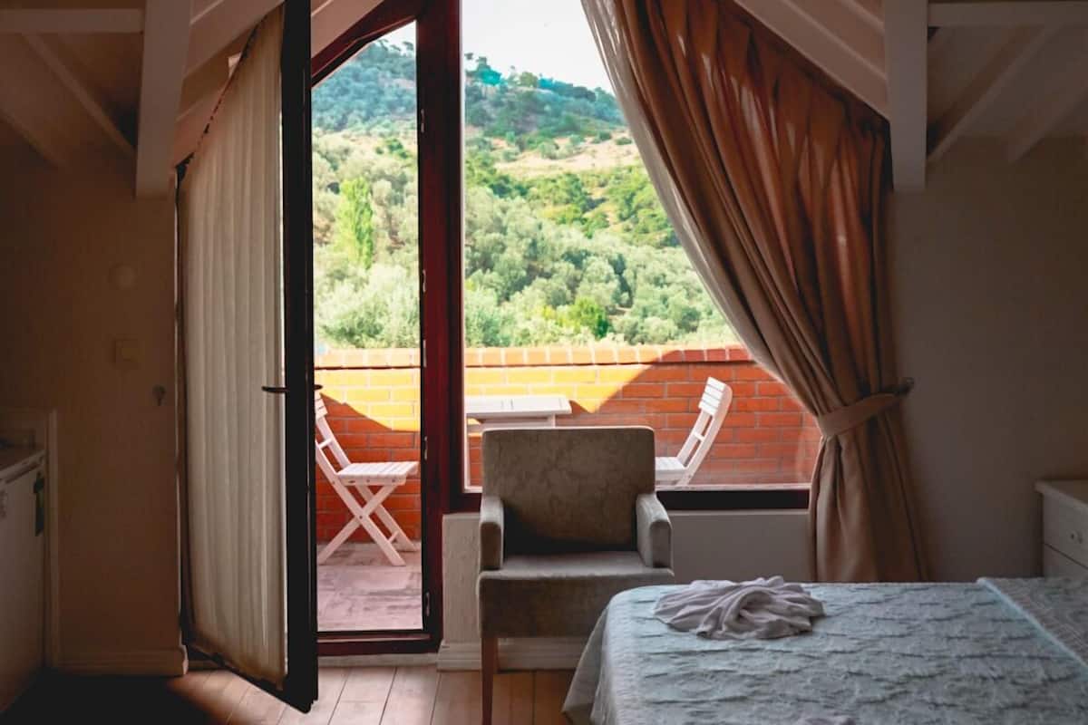 Un dormitorio con cama, una silla y vistas a una colina.