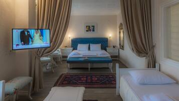 Une chambre d’hôtel avec un lit simple, une petite table de chevet, une chaise, un téléviseur fixé au mur et une fenêtre avec des rideaux.