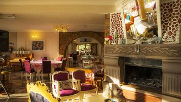 A dining area with a brick archway, a fireplace, and a variety of chairs and tables.