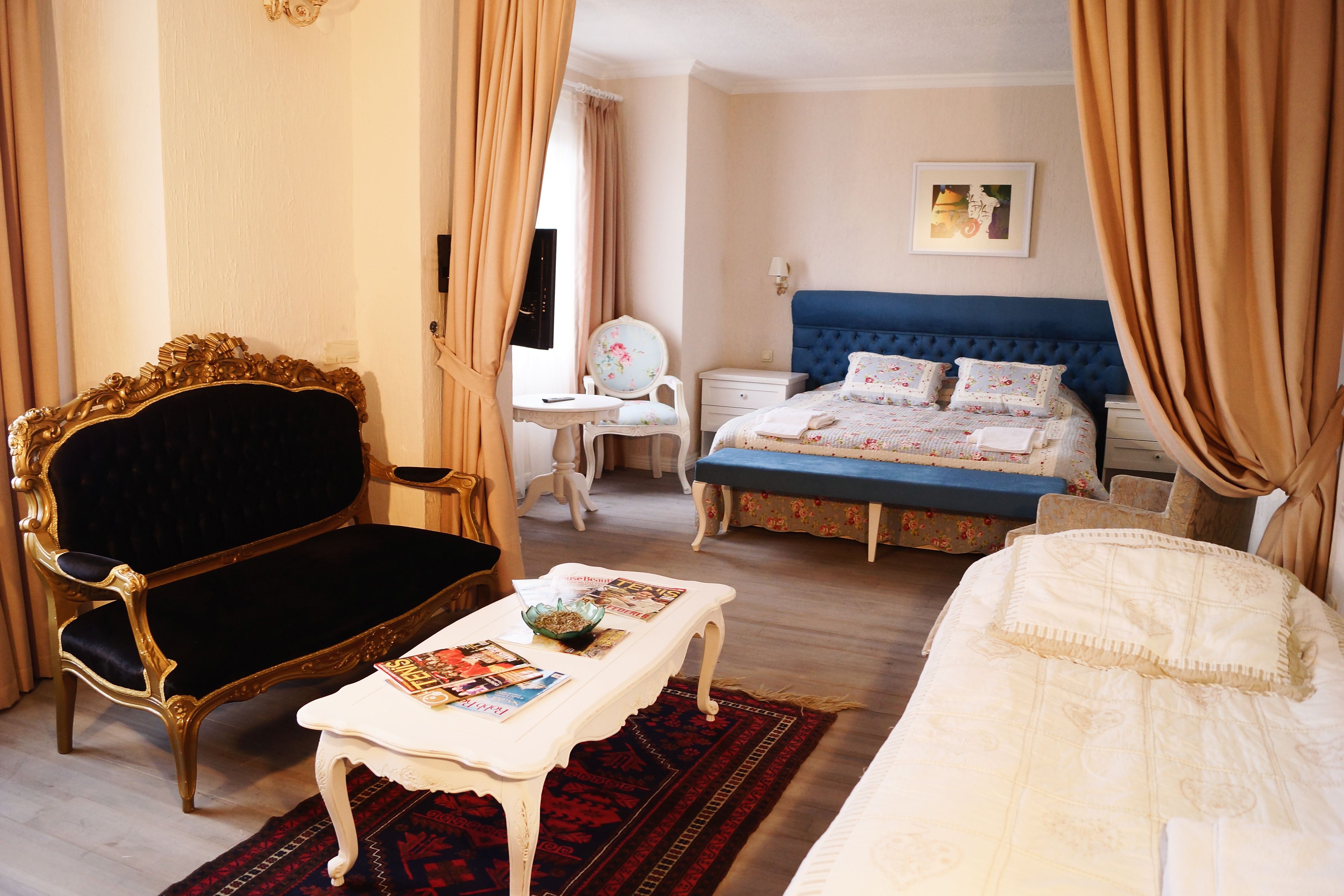 A room with a large bed, a chair, a small table, and a desk.