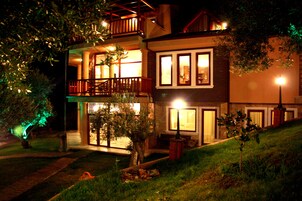 Una casa de dos pisos con balcón, un ventanal grande y una entrada bien iluminada.