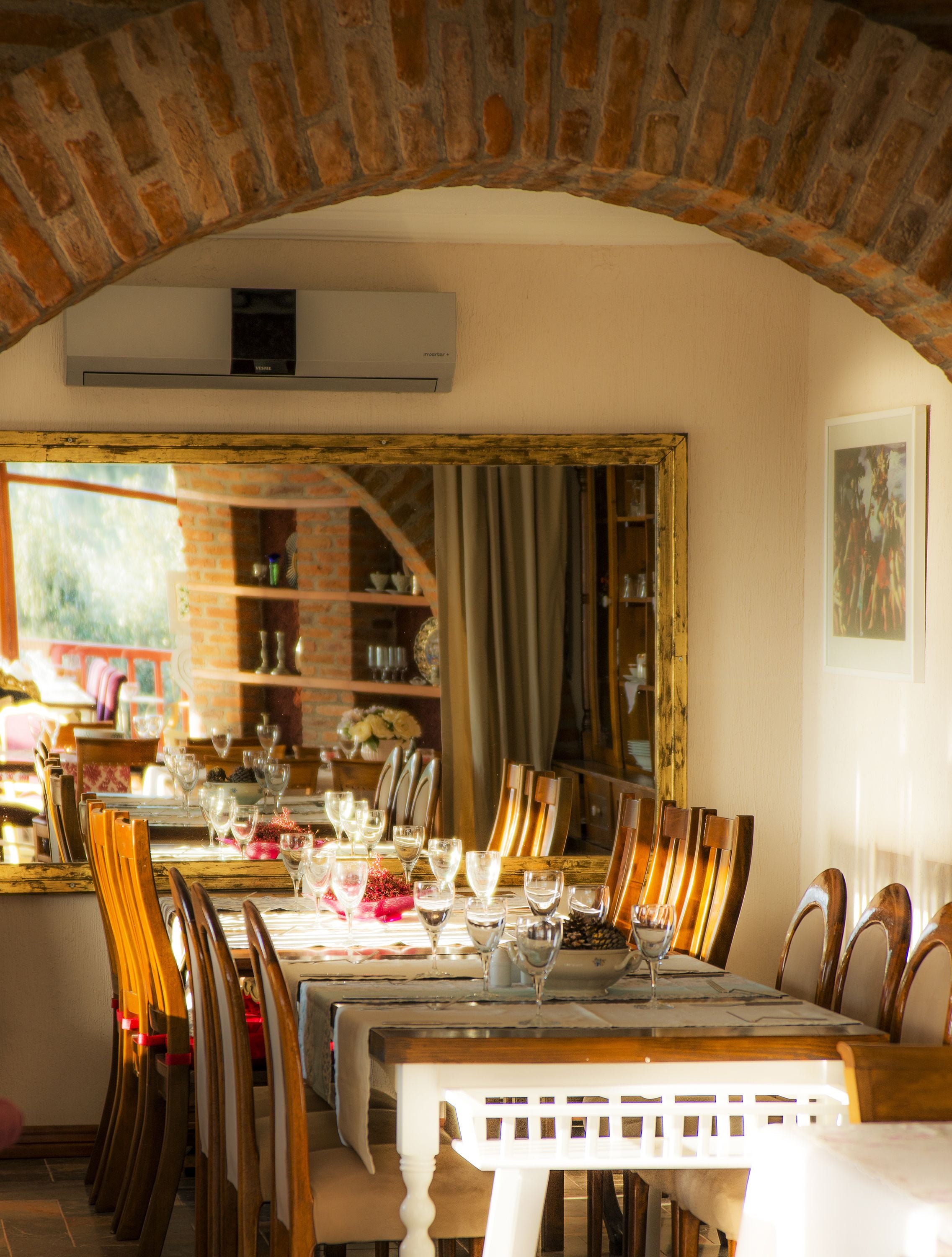 Un comedor con un arco de ladrillo, una mesa lista para comer y vistas a una cocina.