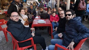 A group of people seated at a red table with a white tablecloth, under a white canopy. - Piazza Marina (Palermo)