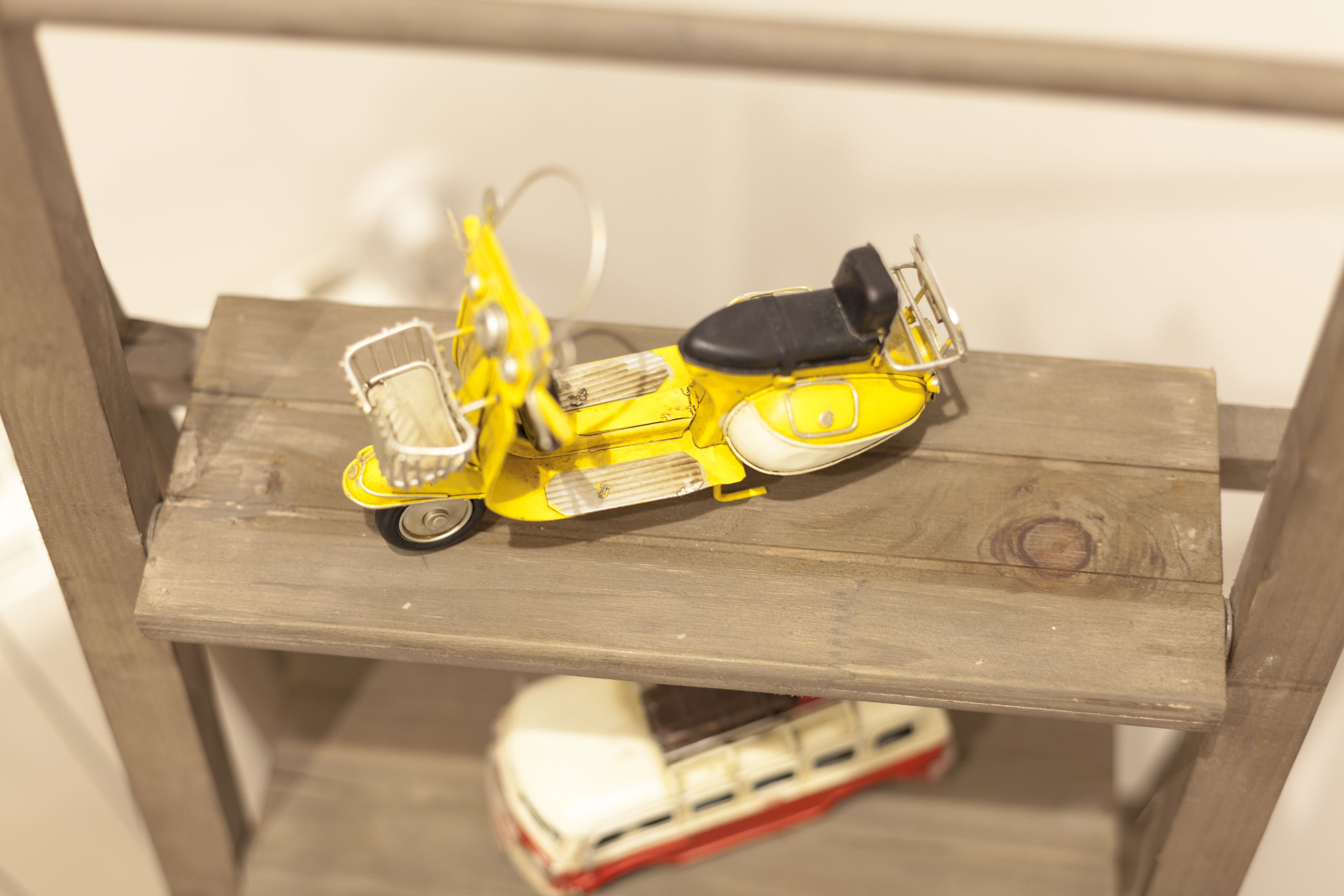 Un scooter jaune sur une étagère en bois.