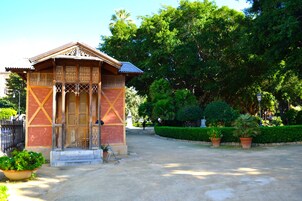 Un piccolo edificio di legno tradizionale, con elaborate sculture, un tetto in tegole e un'area d'ingresso pavimentata con piante in vaso.