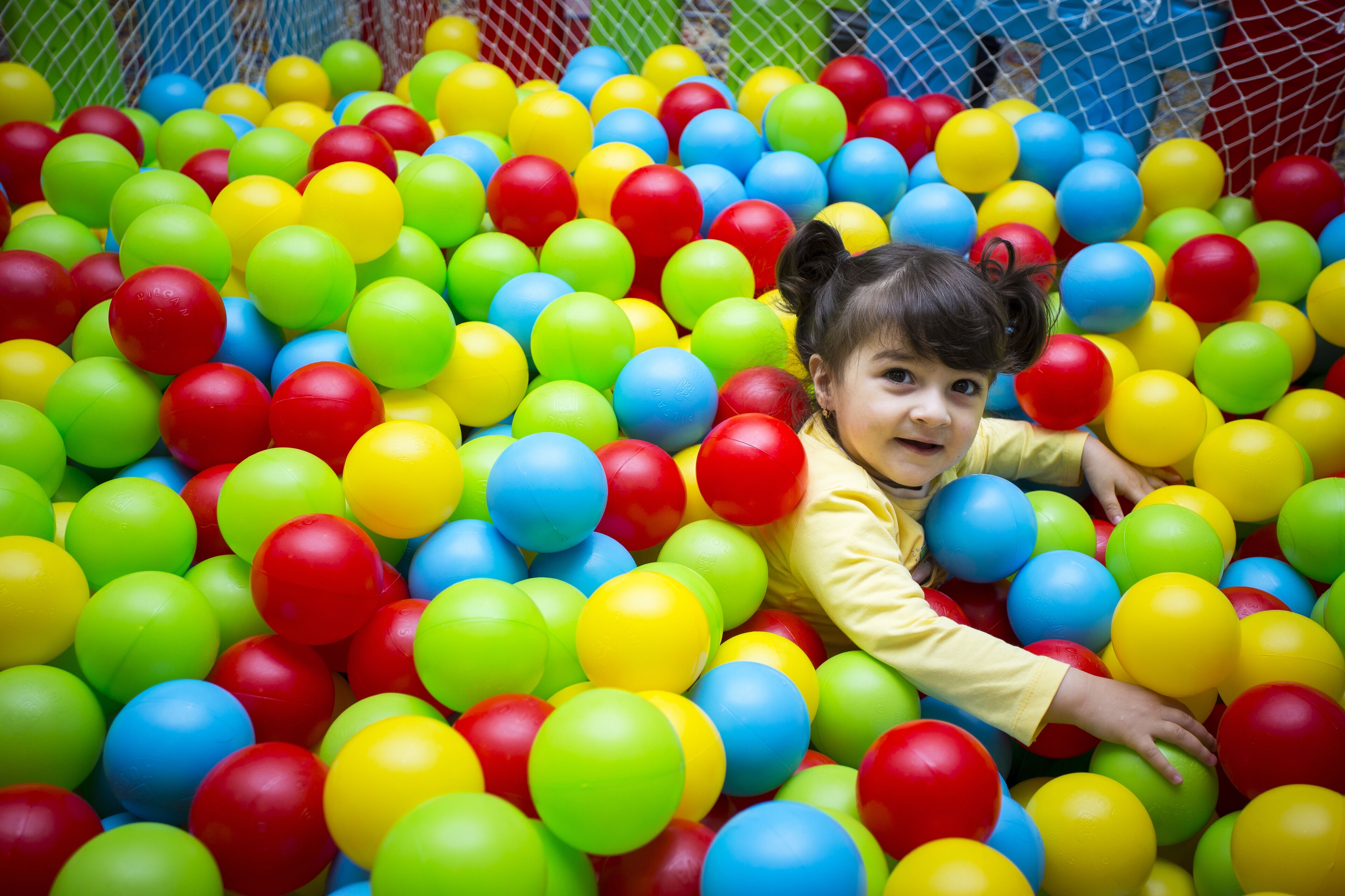 Niño jugando en una piscina de pelotas de varios colores.