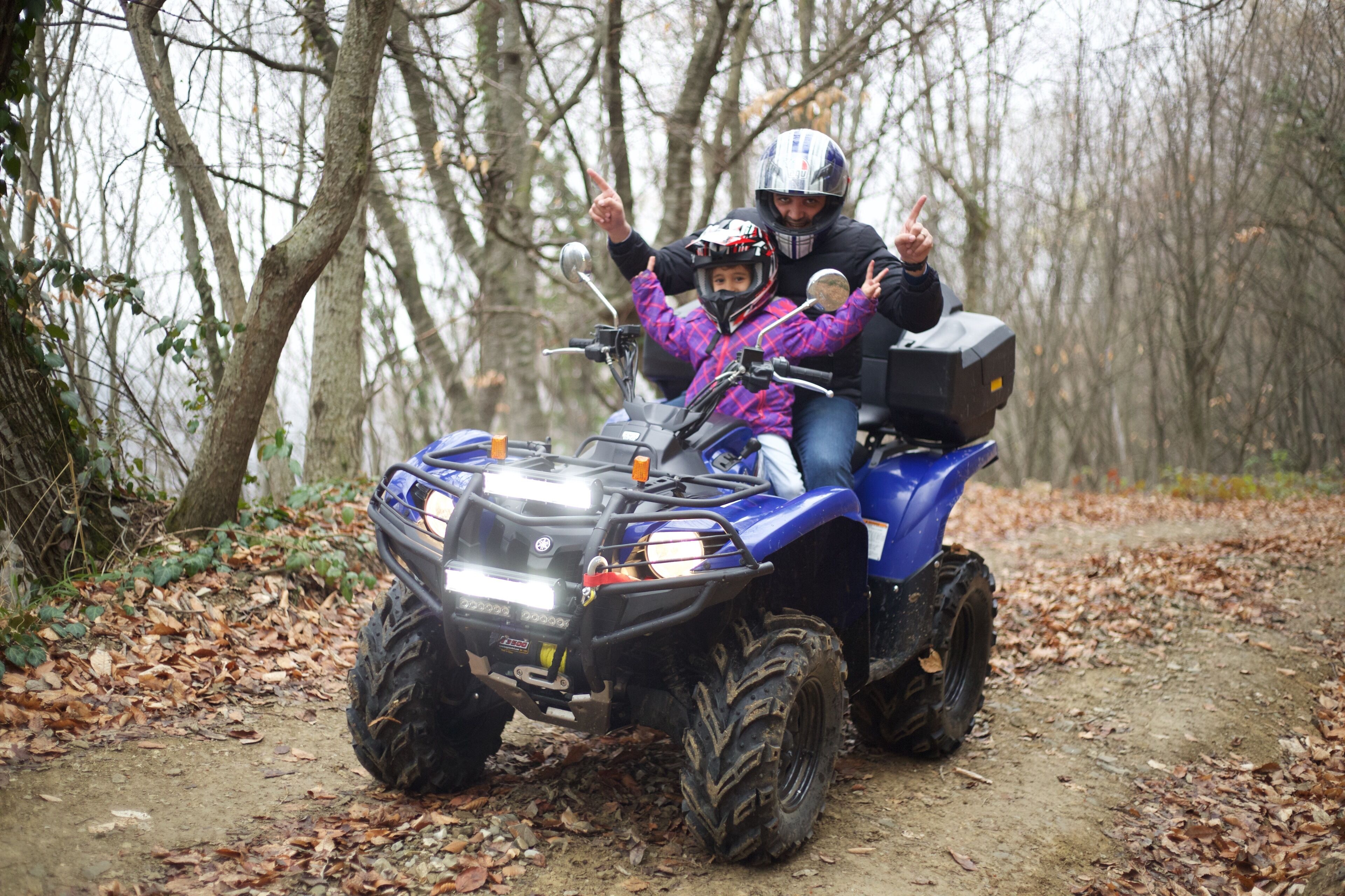 Un quad blau amb dues persones, una d'elles assenyalant cap amunt.