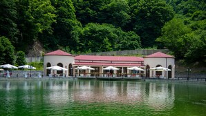 Ein Gebäude am Seeufer mit Außenbestuhlung und rotem Dach.