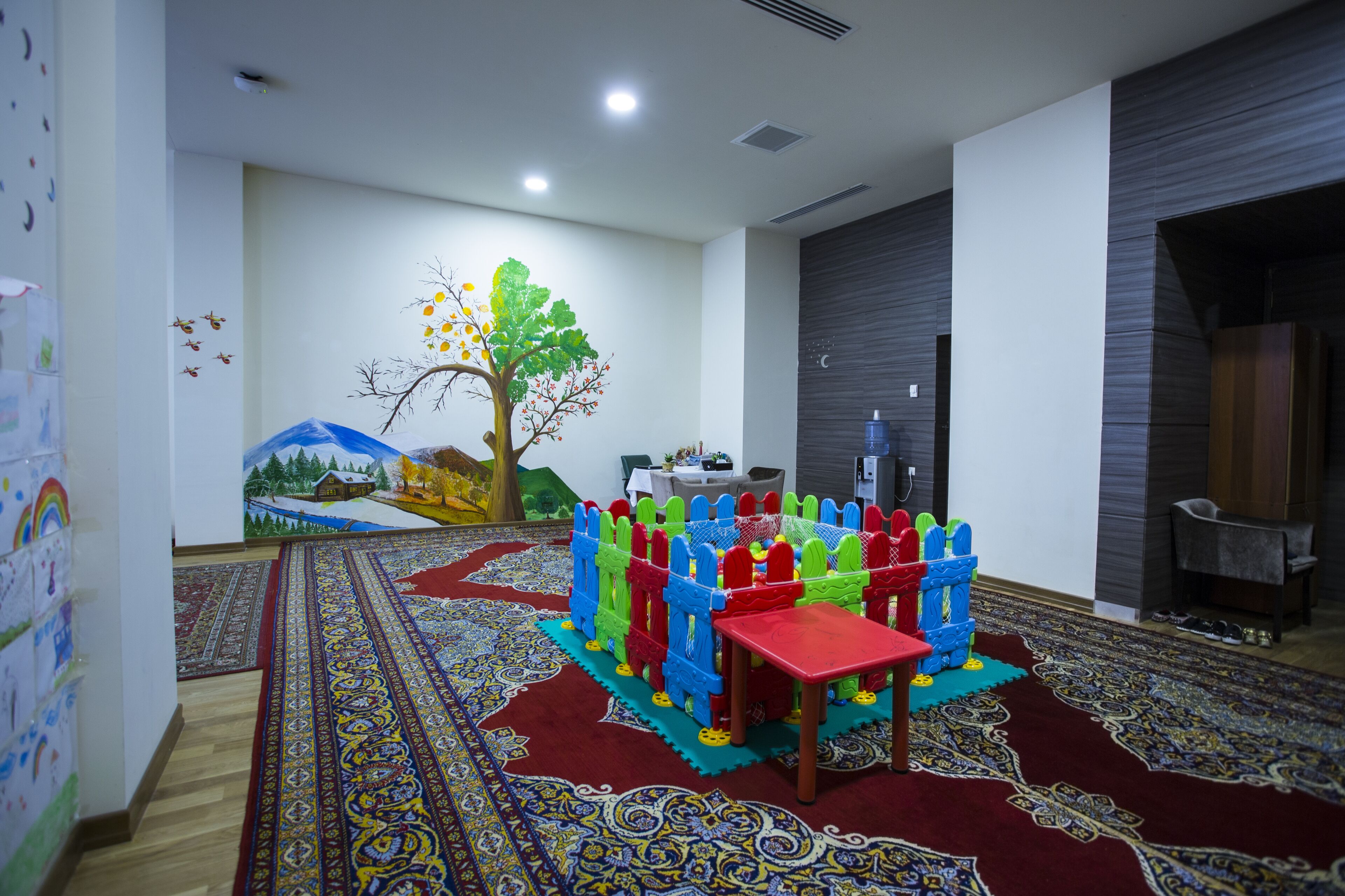 A room with a colorful play area, a large rug, and a mural on the wall.