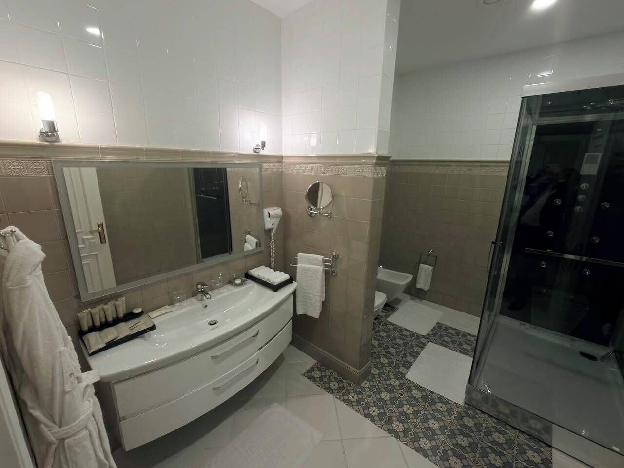 A modern bathroom with a large mirror, a bathtub, a shower, and a toilet.