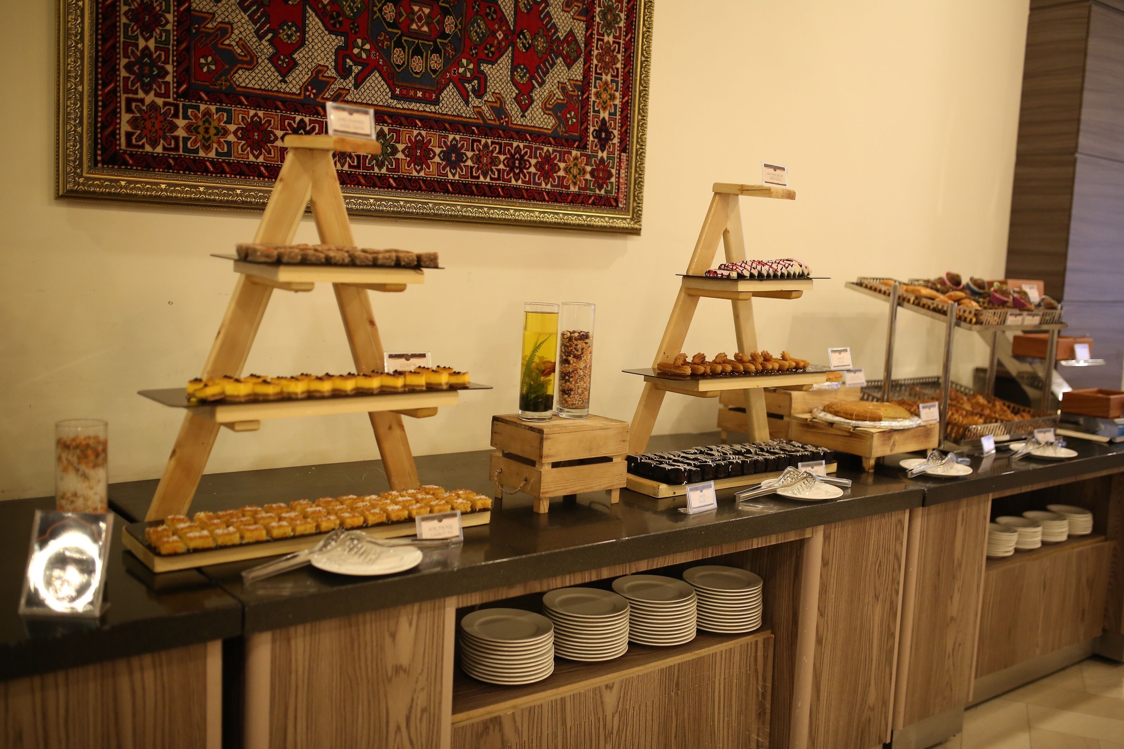 A buffet setup with multiple serving stations, including trays of pastries and desserts, and a variety of condiments and beverages.
