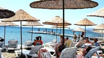 Een privéstrand, ligstoelen aan het strand, parasols