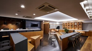 A modern hotel lobby with a reception desk, seating areas, and a coffee bar. - Hotel Etwas Tenjin (Fukuoka)