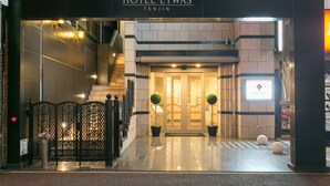 The entrance to Hotel Etwas in Tenjin, featuring a modern design with a glass door, a staircase, and potted plants. - Hotel Etwas Tenjin (Fukuoka)