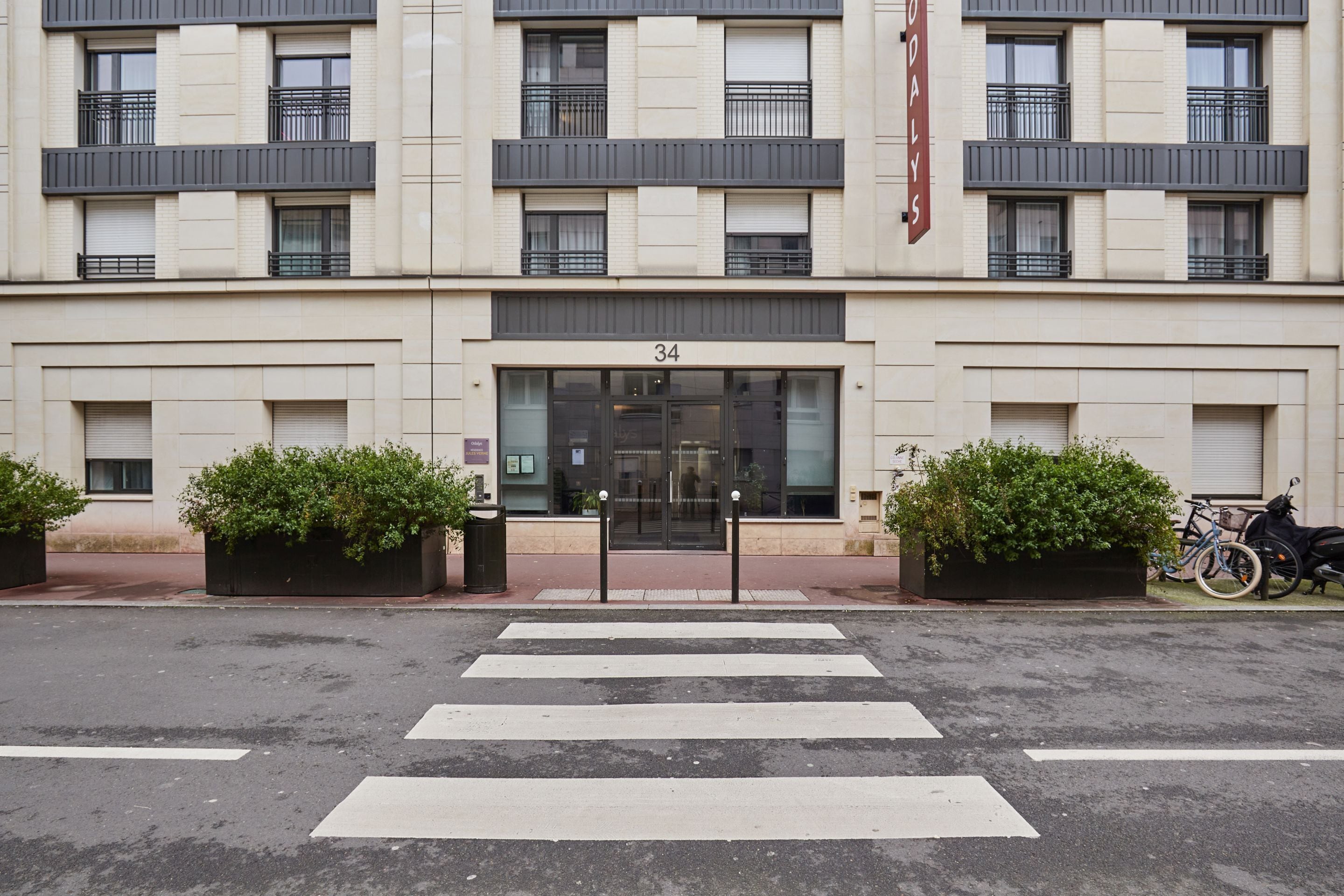 A modern building with a large entrance, numbered 34, and a sign reading "Hotel".