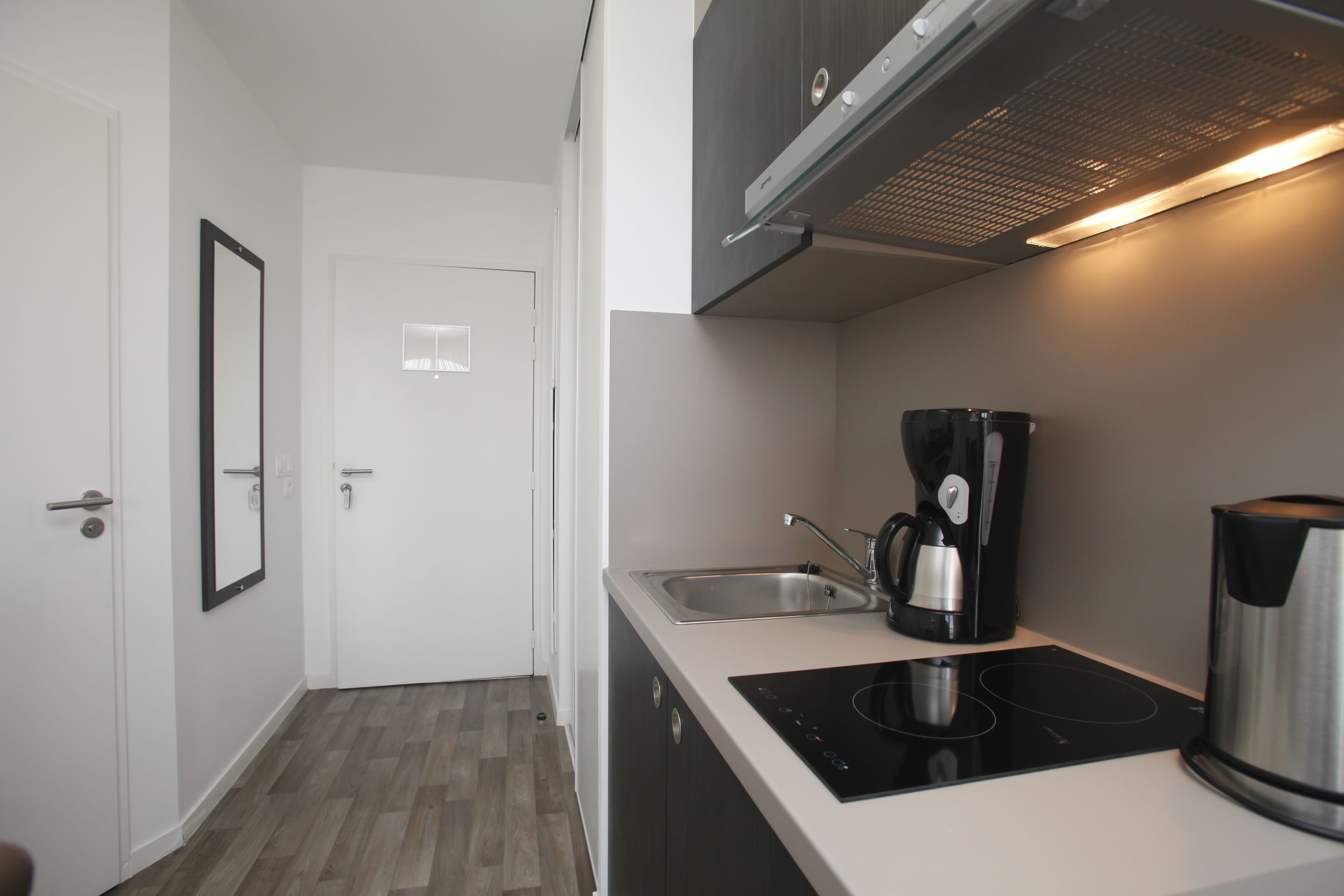 A modern kitchen with a built-in stove, a coffee maker, and a kettle.