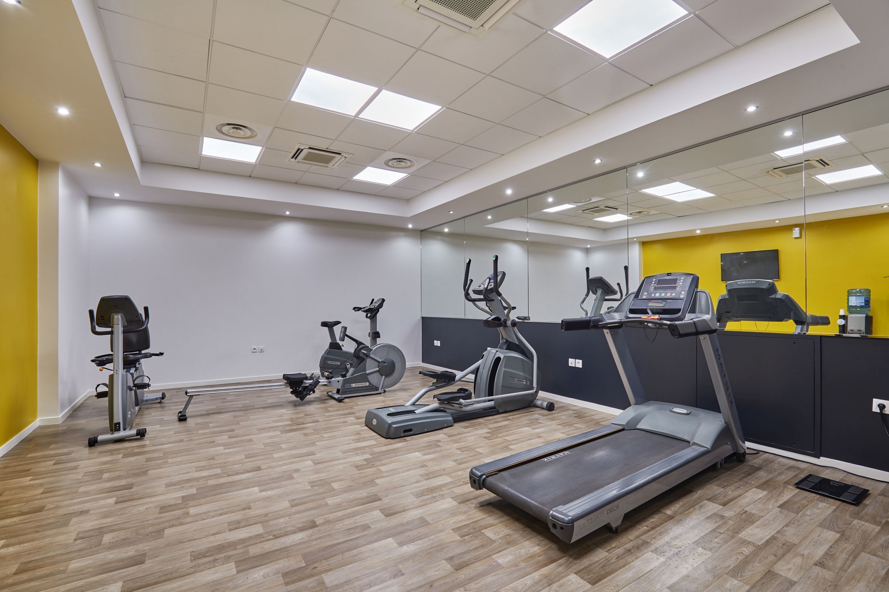 Un gimnasio con cintas de correr, bicicletas estáticas y una máquina de remo.