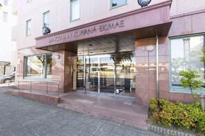 Der Eingang eines Gebäudes mit einem Schild, auf dem 'SANCO IN KUWANA EKIMAE' steht.