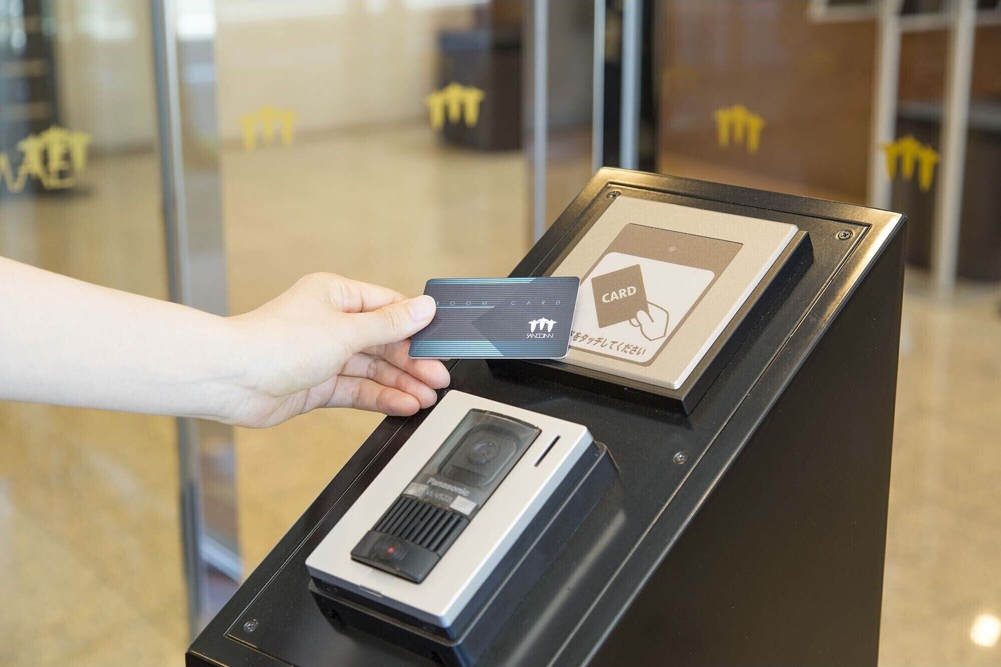 A hand holding a card in front of a card reader.