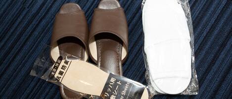 A pair of brown shoes and a white shoe cover on a striped fabric background.