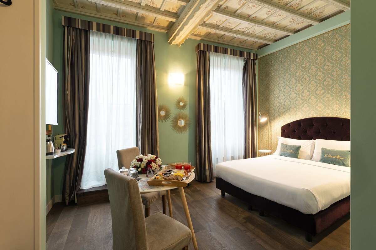 Una camera d'albergo con un letto, una scrivania e la colazione, oltre a tende.