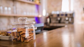 Un tarro de vidrio lleno de galletas sobre una mesa de madera en un bar.