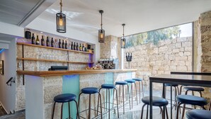 Zona de bar con pared de piedra, mostrador de madera y taburetes.