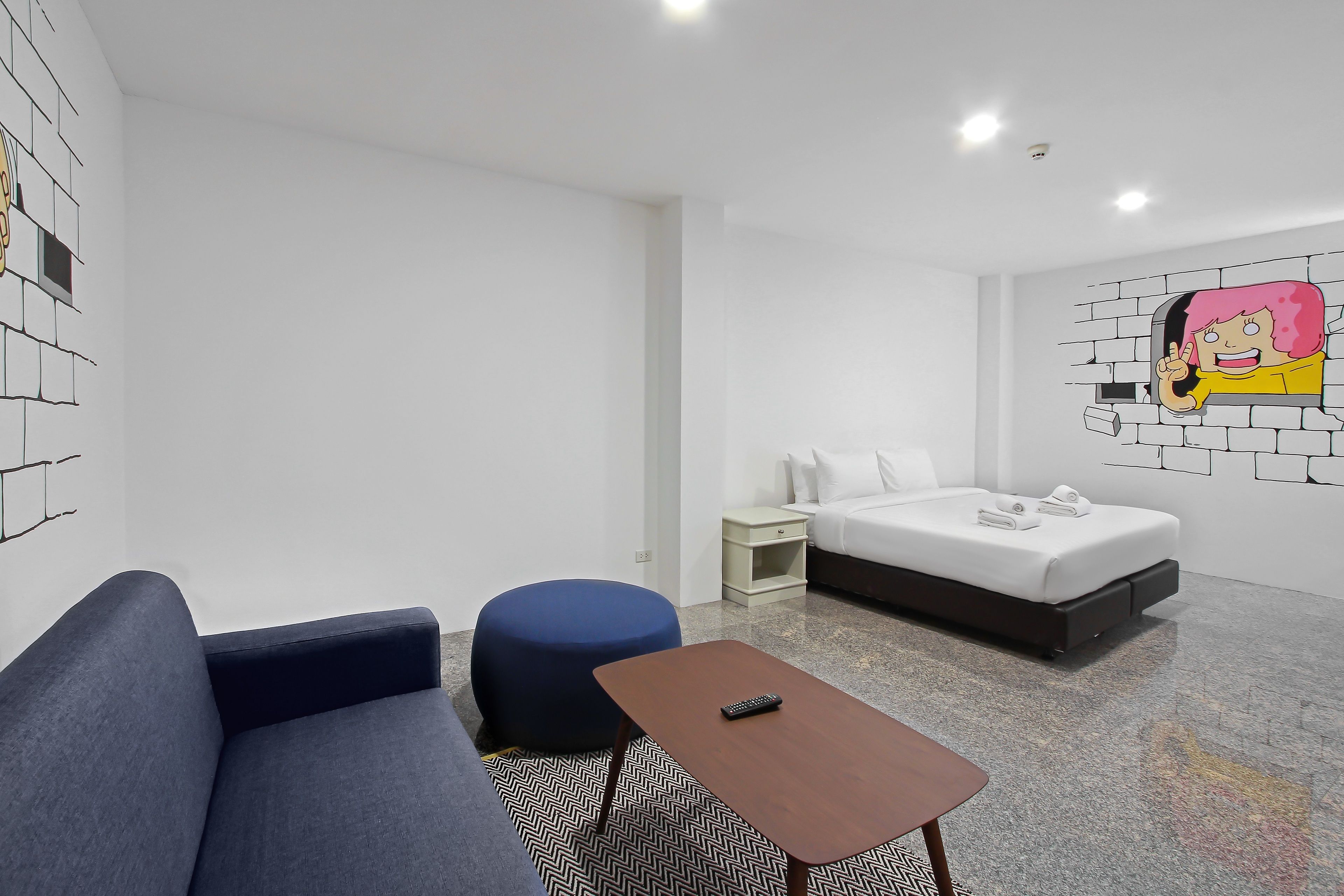 Een moderne hotelkamer met een bank, voetenbankje, nachtkastje en een bed.