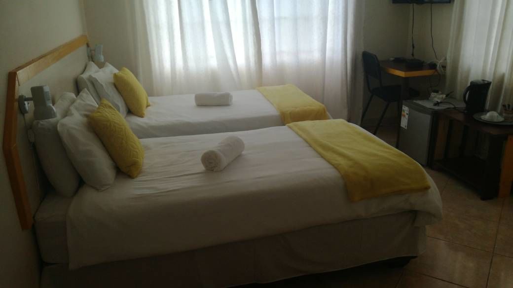 Una habitación de hotel con dos camas, un escritorio, una silla y un televisor.