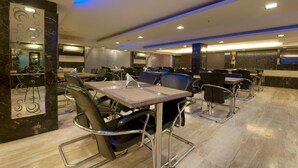 Un comedor moderno con paredes de mármol, sillas negras y mesas.