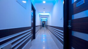 Un pasillo con una puerta de madera que tiene el número 207 y un techo iluminado en azul.