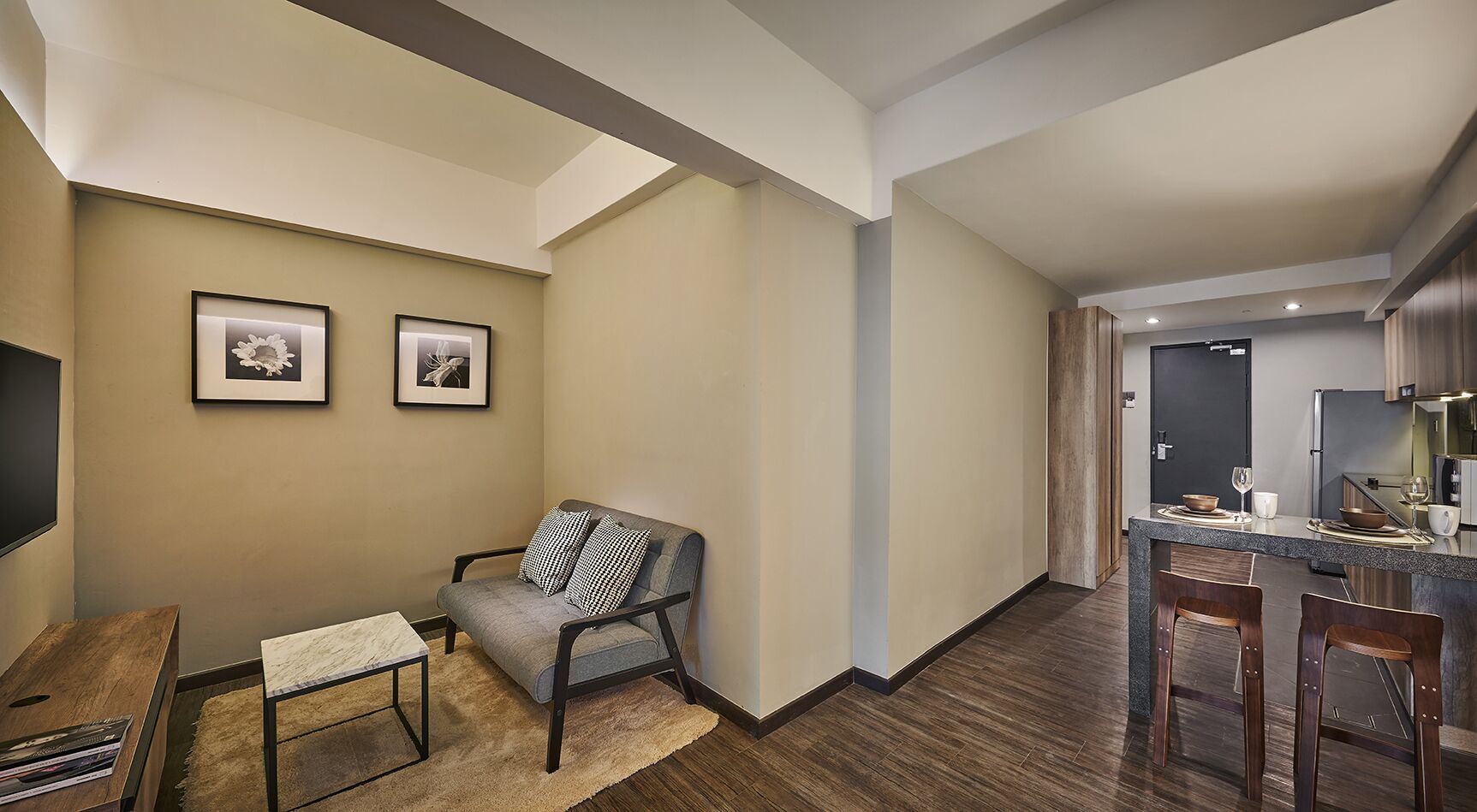 A modern living room with a grey sofa, a small table, and two framed pictures on the wall.