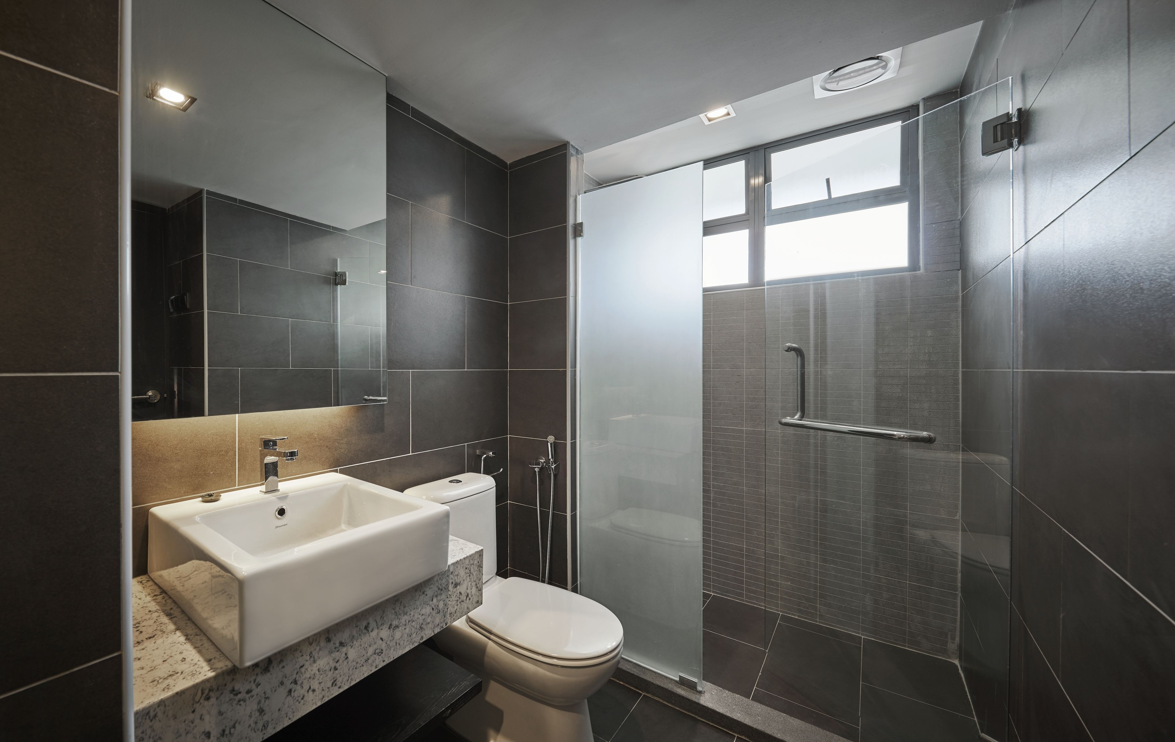 A modern bathroom with a large mirror, a sink, and a toilet.