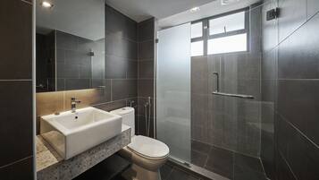 A modern bathroom with a large mirror, a sink, and a toilet.