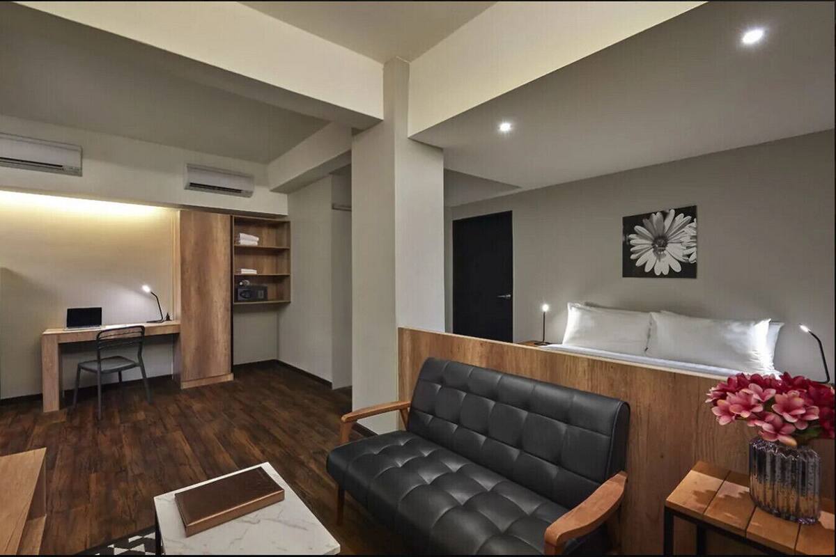 Ein kompakter Wohnraum mit Küchenzeile, Sofa, Schreibtisch und Fernseher.
