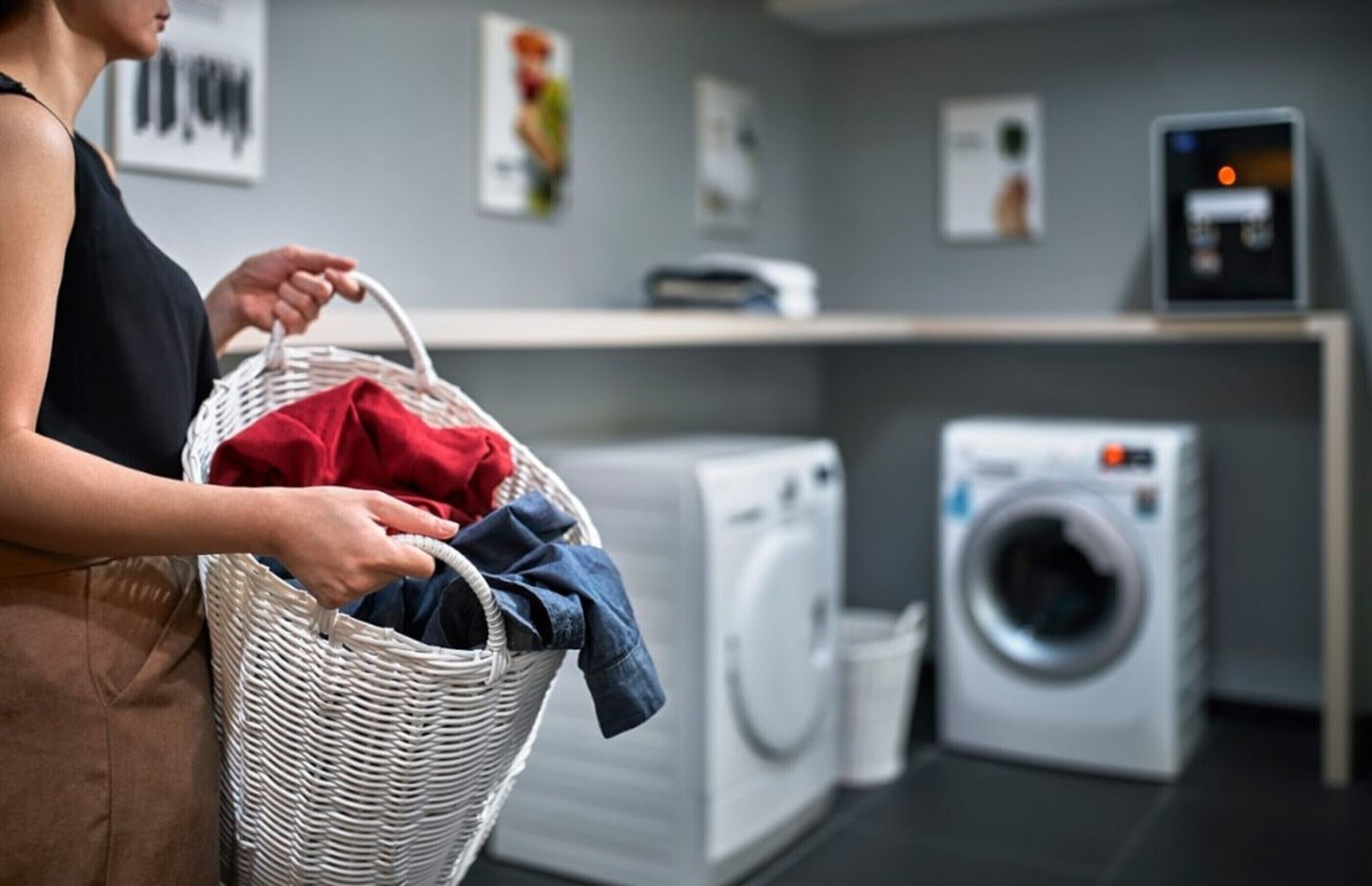 A laundry room with a basket of clothes, a washing machine, and a dryer.