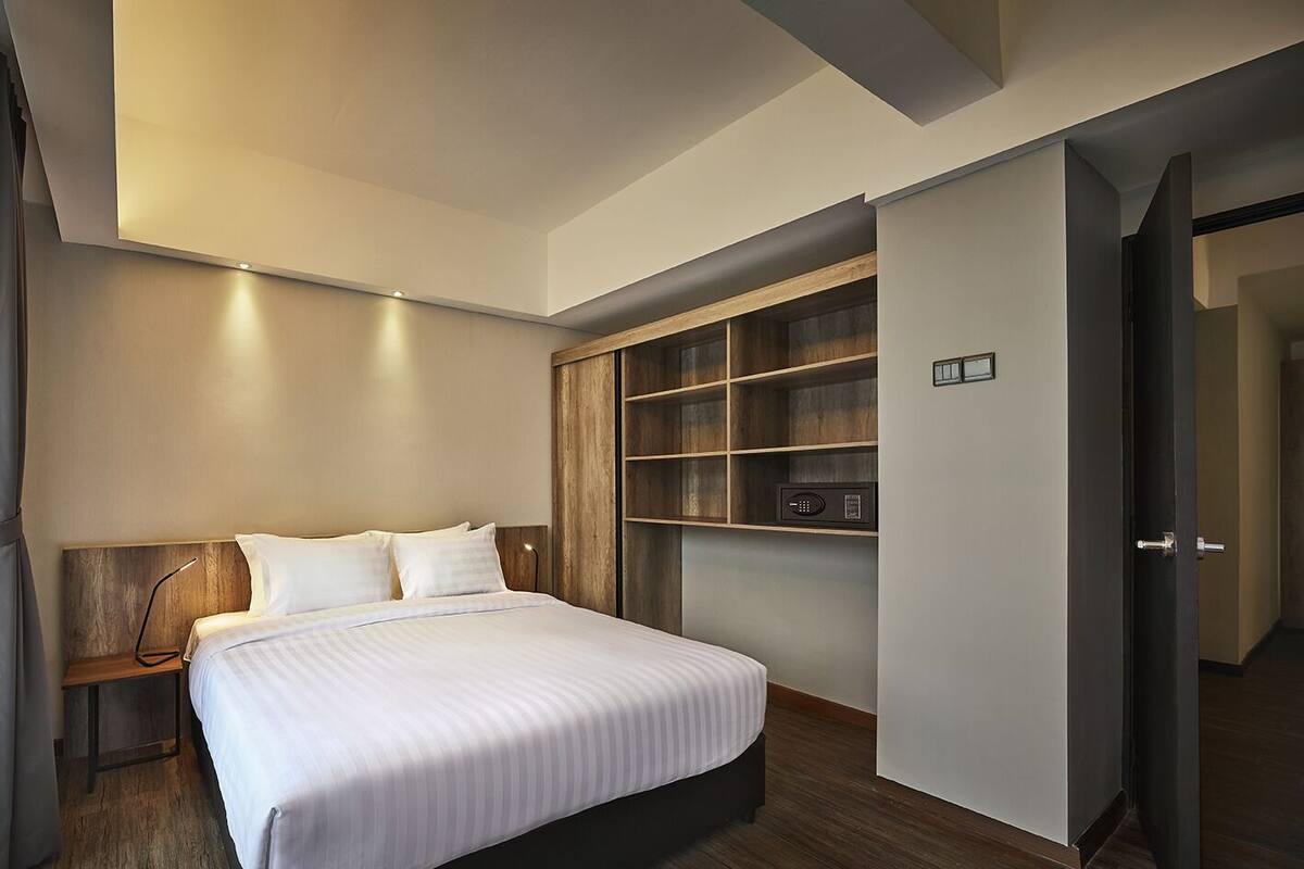 Ein modernes Hotelzimmer mit einem großen Bett, integrierten Holzböden und einem minimalistischen Design.