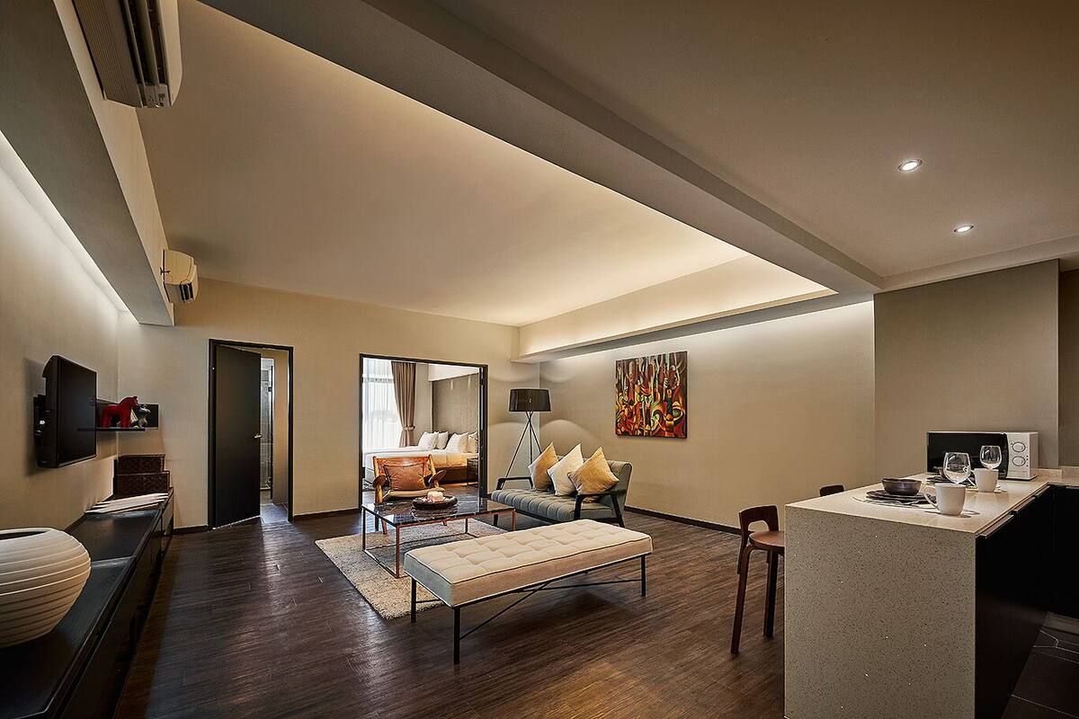 Ein modernes Hotelzimmer mit einem großen Bett, einer Sitzecke mit Sofa und Sesseln, einem Essbereich mit Tisch und Stühlen sowie einer Küche mit Mikrowelle und Toaster.