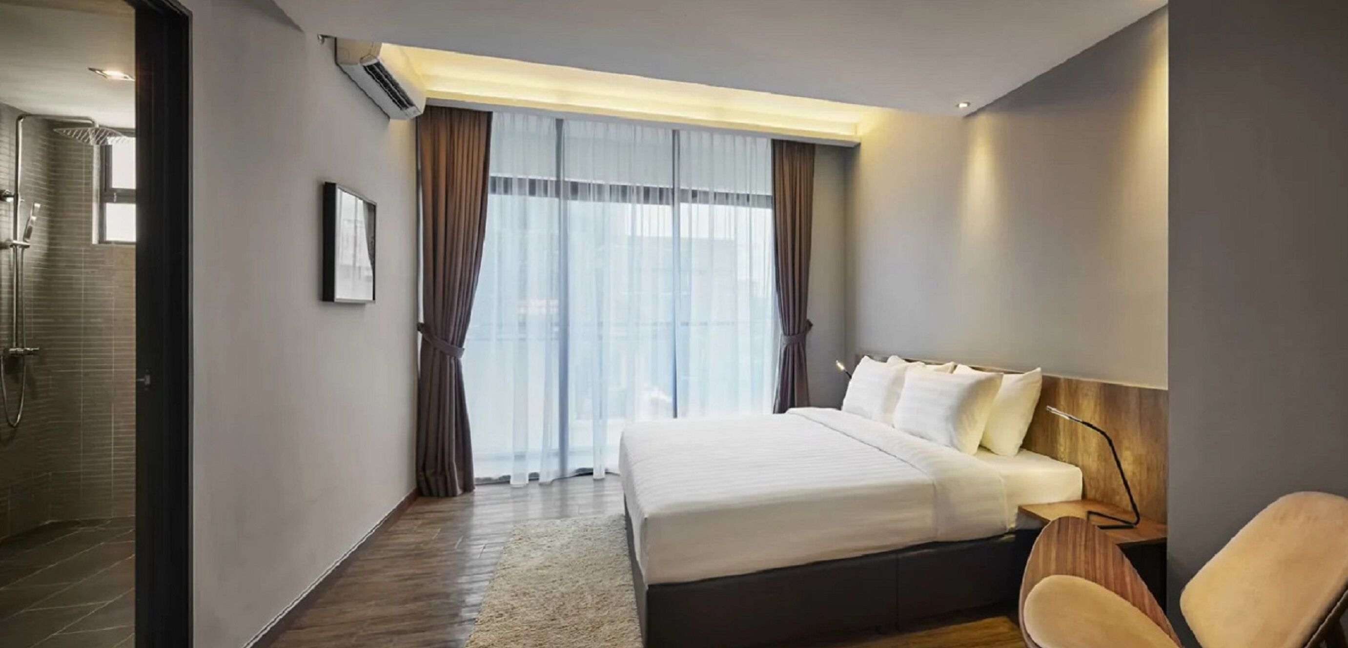 Une chambre d’hôtel moderne équipée d’un grand lit, d’une table de chevet, d’une chaise et d’un espace douche.