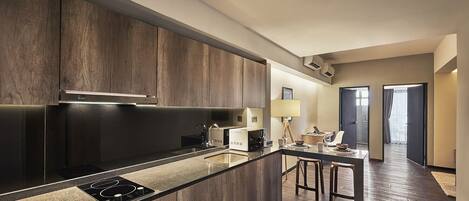 A modern kitchen with dark wood cabinetry, a central island with a built-in stove, and a dining area with a table and chairs.