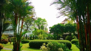A well-maintained garden with various plants and trees, a pathway, and traditional architecture in the background. - Swankaburi Boutique Hotel (Sawankhalok)