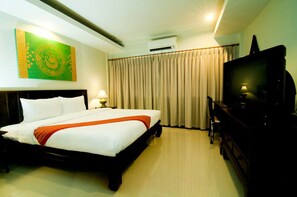 A hotel room with a bed, a television, a desk, and a painting on the wall. - Swankaburi Boutique Hotel (Sawankhalok)
