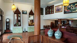 A lobby with a wooden reception desk, seating area, and a large vase. - Swankaburi Boutique Hotel (Sawankhalok)