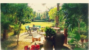 A garden with a table and chairs, surrounded by potted plants and trees. - Swankaburi Boutique Hotel (Sawankhalok)