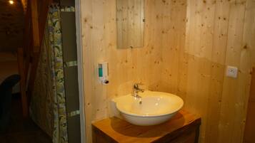 Une salle de bain en bois avec un lavabo blanc, un miroir et un rideau de douche.