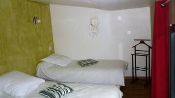 Une chambre avec deux lits, un rideau rouge et une horloge murale.