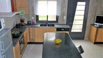 A modern kitchen with a central island, built-in appliances, and a large window providing natural light.