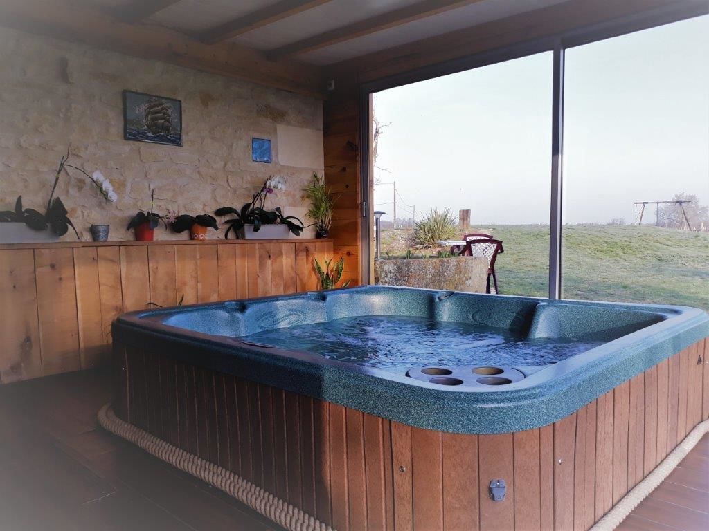 Een hottub in een houten ruimte met uitzicht op een grasveld.