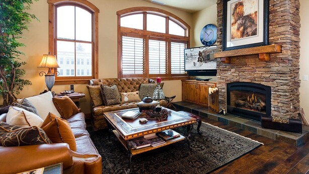 A cozy living room with a fireplace, leather furniture, and large windows.